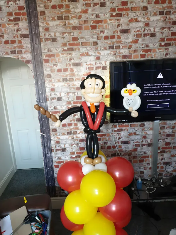 Balloon sculpture of a groom in a tuxedo holding a white bird