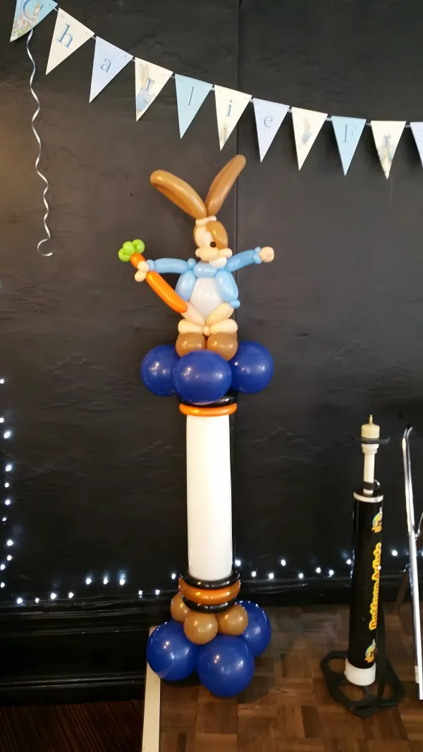 Balloon column topped with a Peter Rabbit sculpture holding a carrot